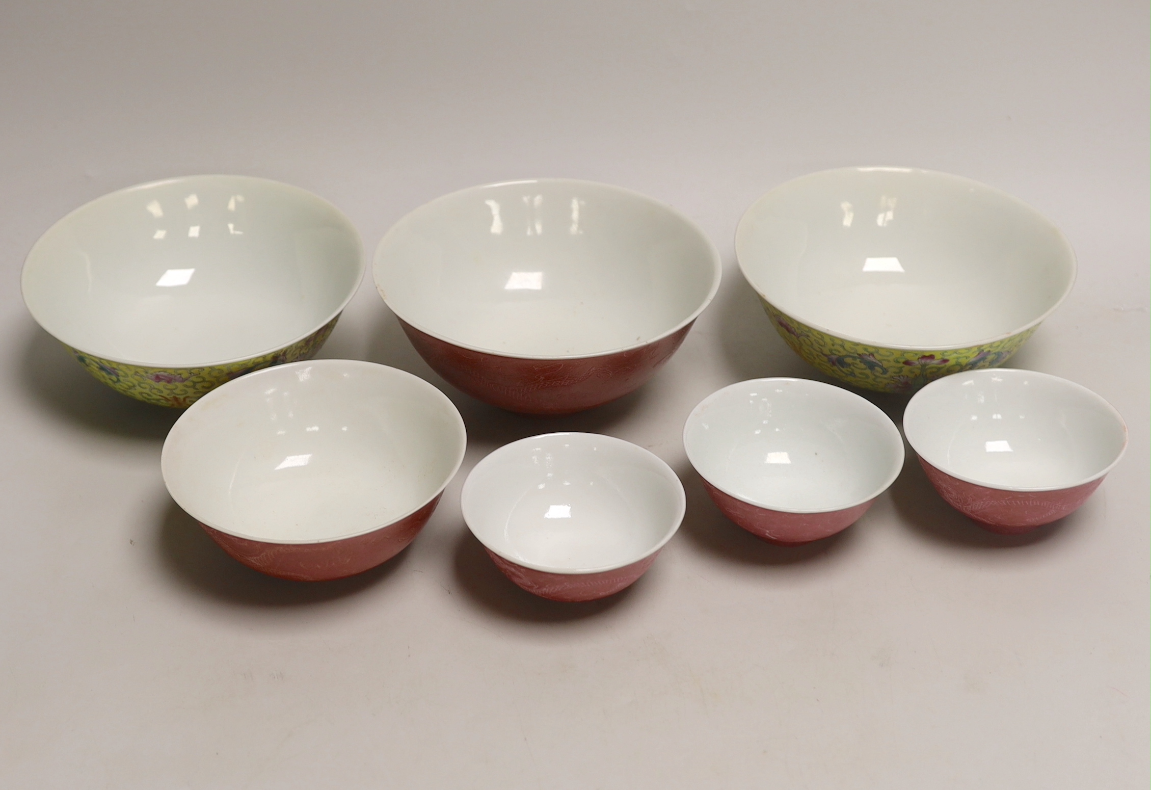 Five Chinese pink monochrome bowls decorated with dragons chasing the flaming pearl together with a yellow ground pair, largest 16cm in diameter